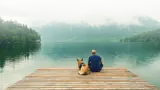 Man and dog sitting on a dock