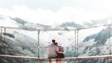 couple sitting on bridge observing a mountain